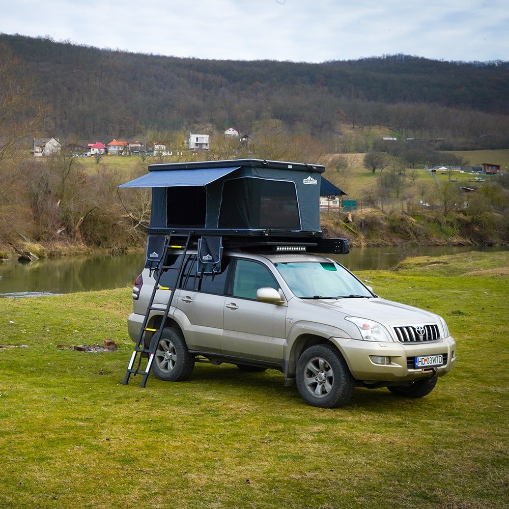 Overlander Traveller aluminium rooftop tent open on an SUV beside a lake